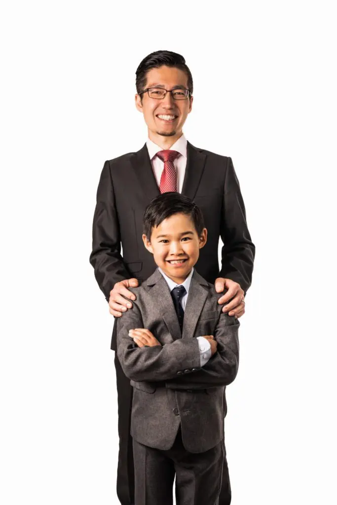Father and son in suits, posed against a white studio backdrop