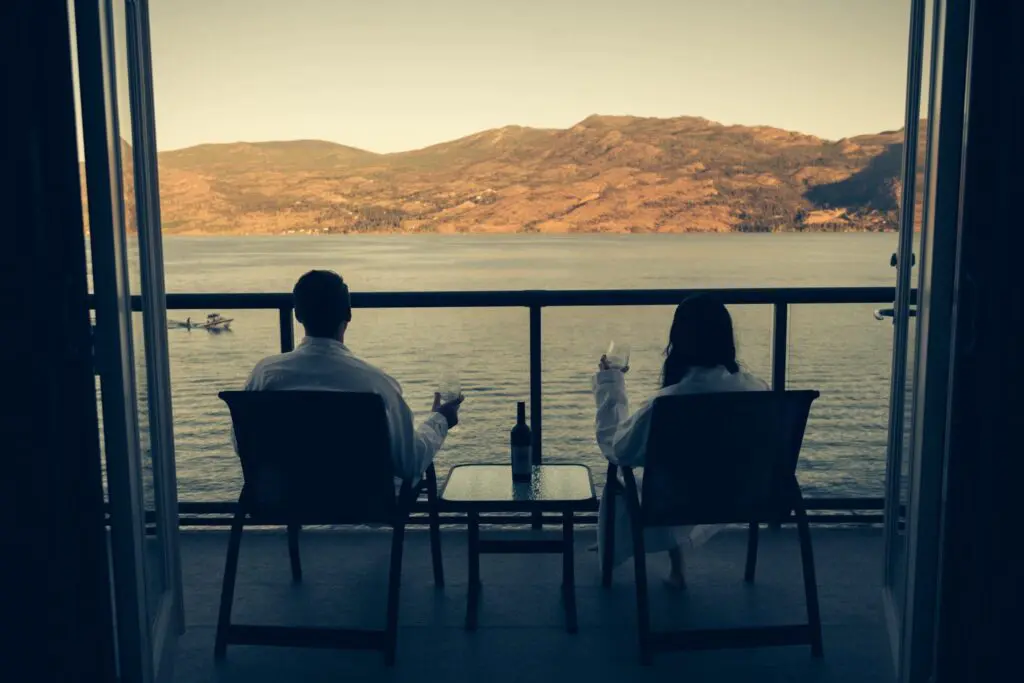 Couple relaxing on a balcony overlooking Okanagan Lake and the hills
