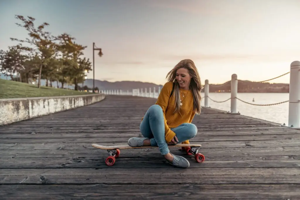 Woman relaxing on a longboard on a lakeside boardwalk at dusk, Kelowna lifestyle photography