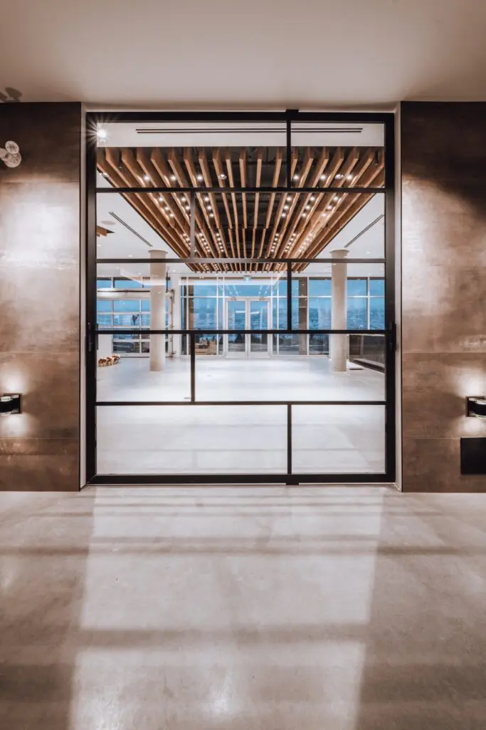 Tall black-framed glass doors opening onto a hall with a slatted wood ceiling at Mt. Boucherie Estate Winery
