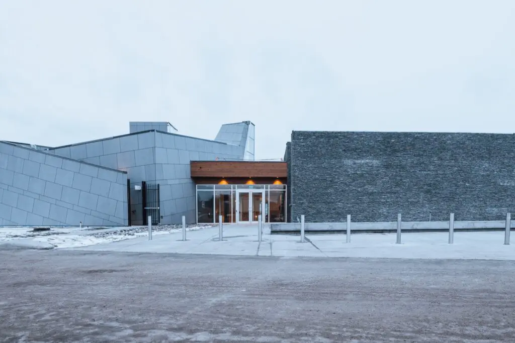 Mt. Boucherie Estate Winery in West Kelowna, with stone and metal walls and a lit glass entrance on a winter day